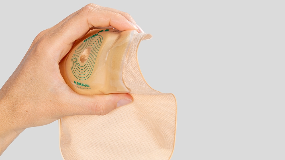 Dışbükey bir stoma torbasını tutan el