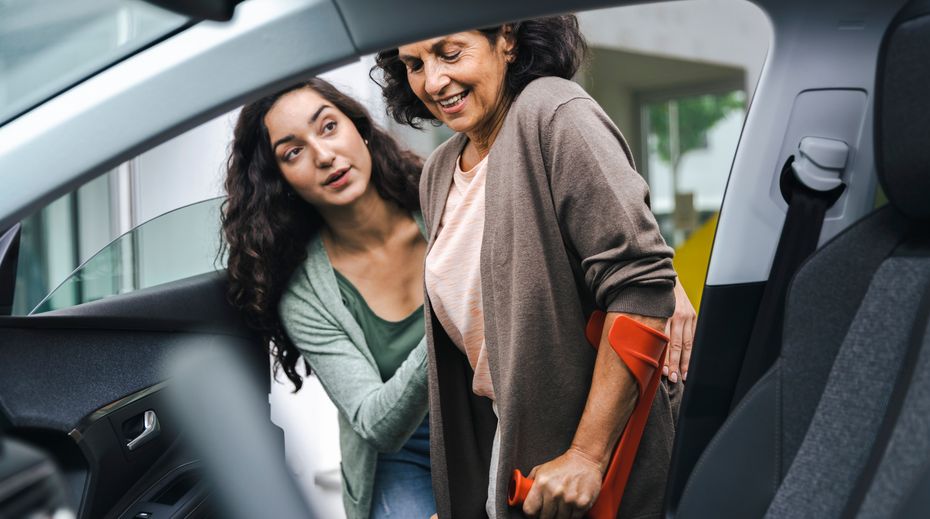 Araca binmesine yardımcı olunan yürüteç kullanan bir hasta.